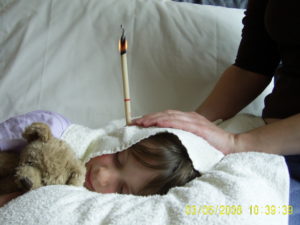 Child with an ear candle in their ear during a treatment session.